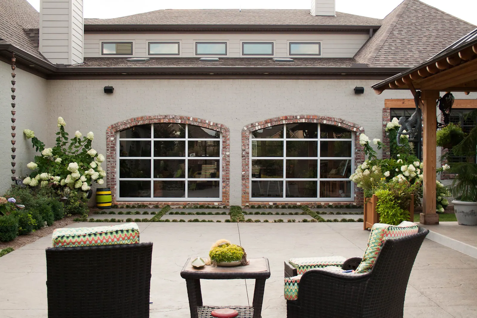 Two Safe-Way Ventana full-view garage doors with arched brick surrounds on a residential courtyard